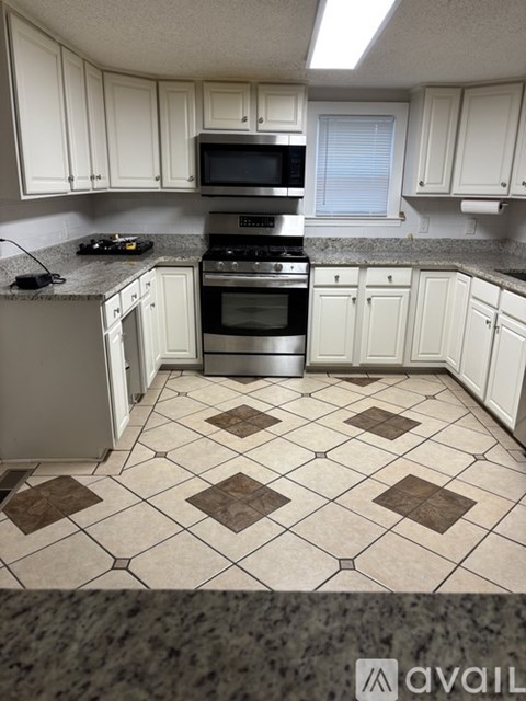 A kitchen with white cabinets and a black stove top oven.