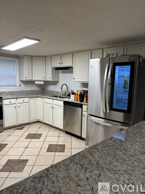 A kitchen with white cabinets and a granite counter.