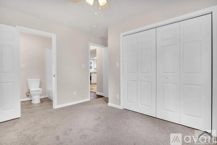 A white bathroom with a toilet and a white wardrobe.
