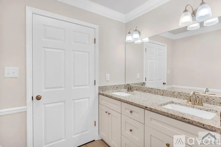 A bathroom with a white door, a granite countertop, and a mirror above the sink.