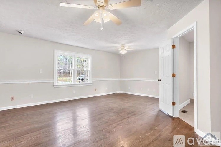 A room with a ceiling fan and wooden flooring.