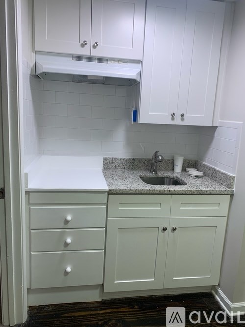 A kitchen with white cabinets and a granite countertop.