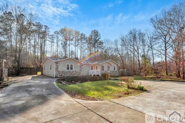 A house with a driveway in front of it surrounded by trees.