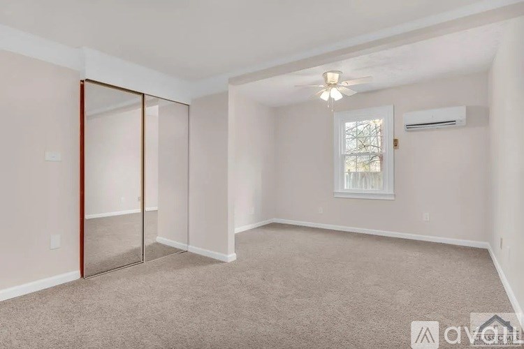 A room with a carpeted floor, a ceiling fan, and a sliding glass door.