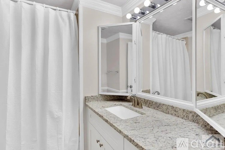 A bathroom with a white shower curtain and a marble countertop.