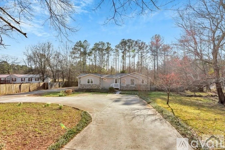 A house with a driveway and trees in the background.