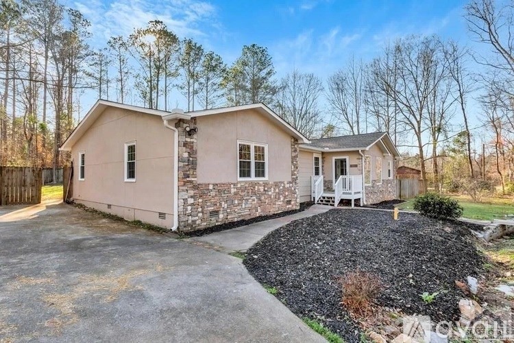 A house with a stone wall and a gravel driveway.