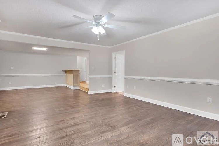 A spacious room with wooden flooring and a ceiling fan.