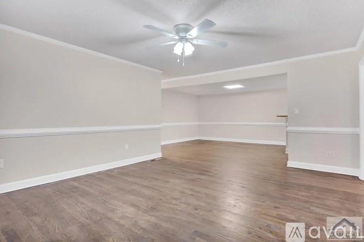 A spacious room with wooden flooring and a ceiling fan.