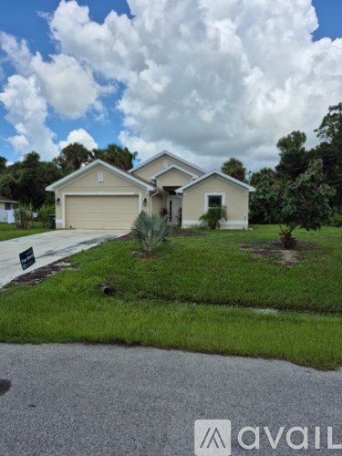 A house with a garage is situated in a grassy area.