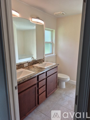 A bathroom with a toilet, sink, and mirror.
