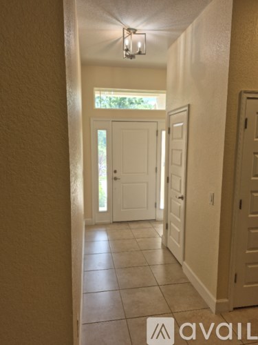 A hallway with a white door and tiled floor.