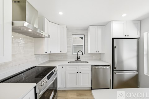 A modern kitchen with white cabinets and stainless steel appliances.