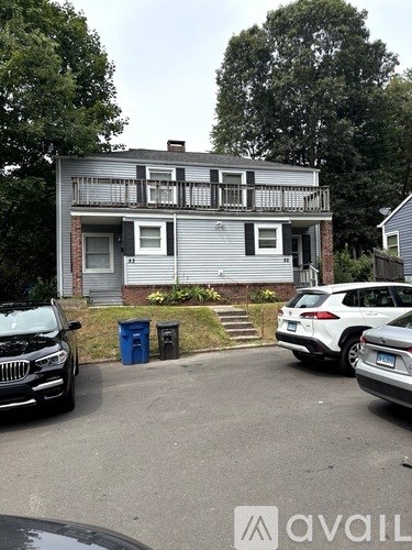 A two-story house with a balcony and a car parked in front.
