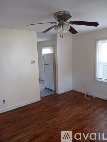 A room with a ceiling fan and wooden floors.