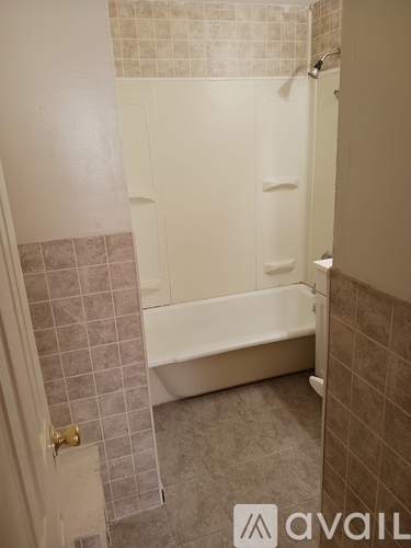 A bathroom with a white tub and tiled walls.