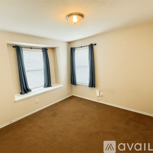 A room with two windows and carpeted floor.