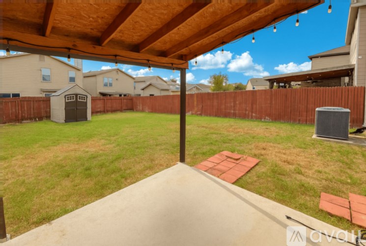 A backyard with a wooden fence and a covered patio area.