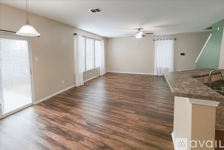A spacious room with wooden flooring and a ceiling fan.