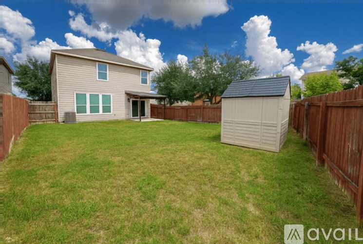A backyard with a house, a shed, and a fence.