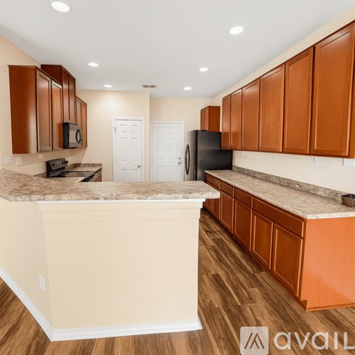 A kitchen with brown cabinets and a black refrigerator.