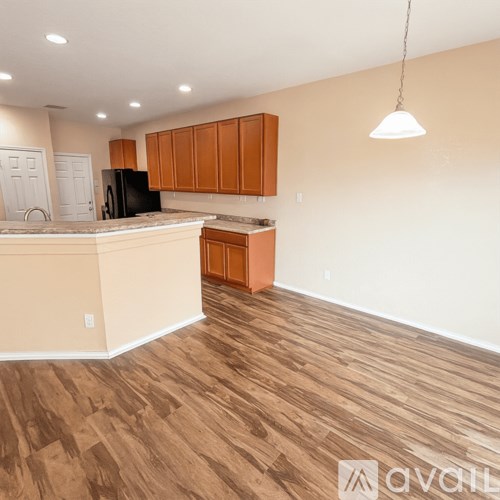 A kitchen with wooden floors and a black refrigerator.