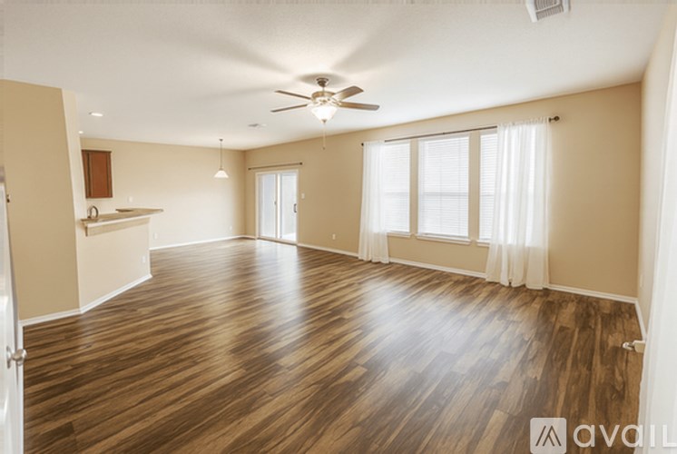 A spacious room with wooden flooring and a ceiling fan.