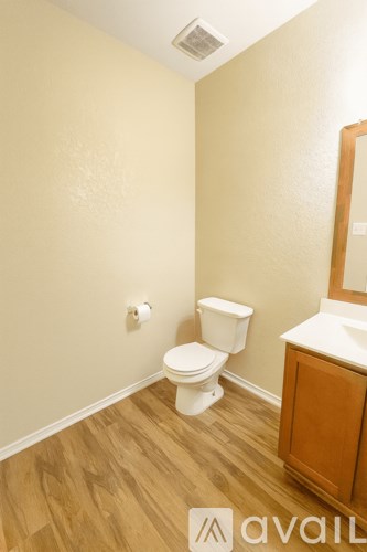 A bathroom with a toilet, sink and wooden floors.