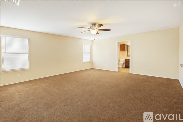 A spacious room with a ceiling fan and carpeted floor.