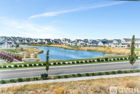 A bridge over a blue lake with houses in the background.