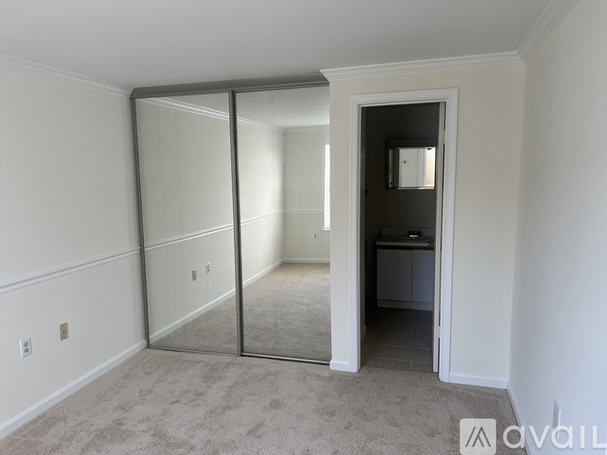 A room with a carpeted floor and a sliding glass door leading to another room.