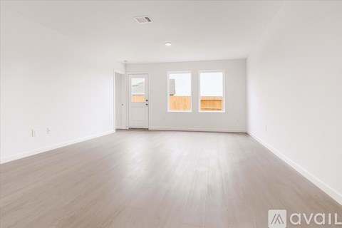 A spacious room with wooden flooring and two doors.