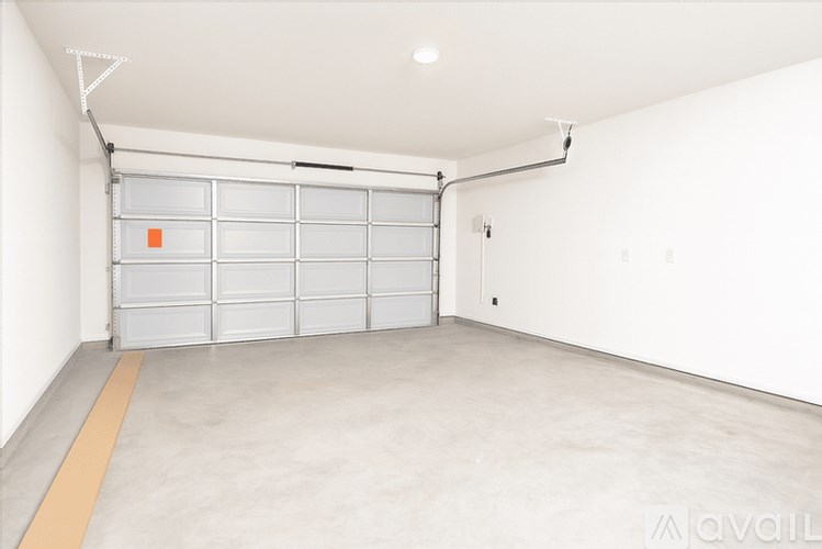 A large empty garage with a white wall and a grey floor.