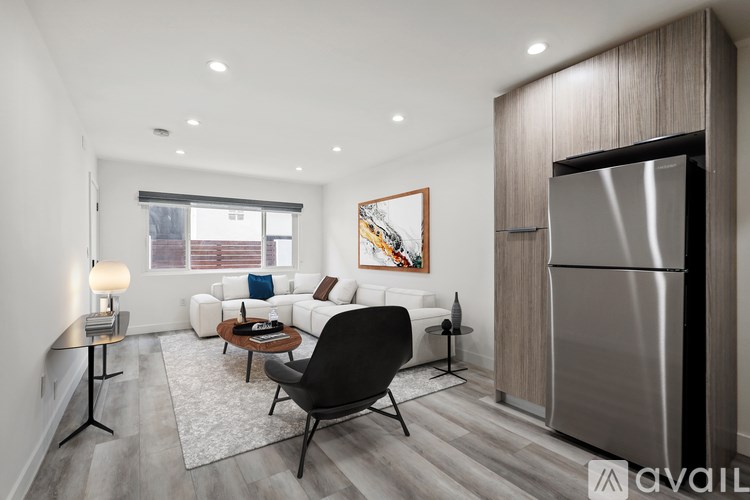 A modern kitchen with a refrigerator, a dining table with chairs, and a painting on the wall.