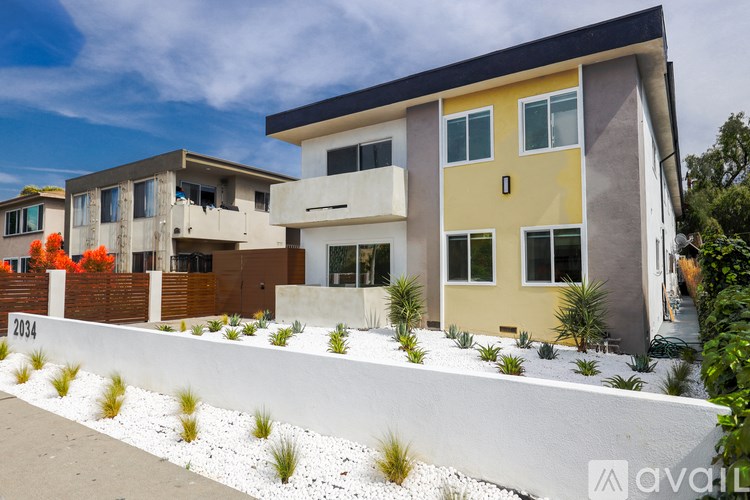 A modern two-story house with a white fence and a yellow front door.