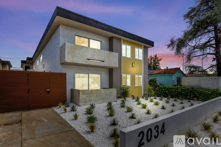 A modern house with a brown garage door and a stone wall with the number 2034 on it.