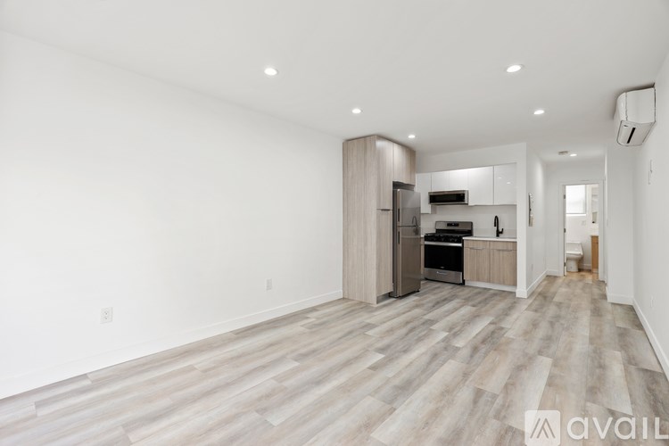 A spacious kitchen with wooden flooring and white walls.