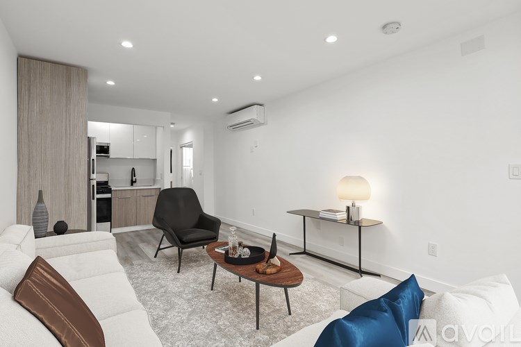 A modern living room with a white couch, a wooden coffee table, and a black chair.