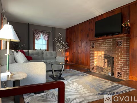 A living room with a grey couch, a fireplace, and a television mounted on the wall.