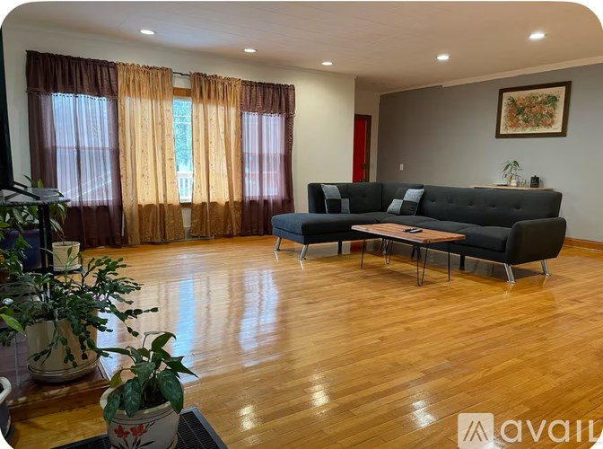 A living room with a black couch and wooden floors.