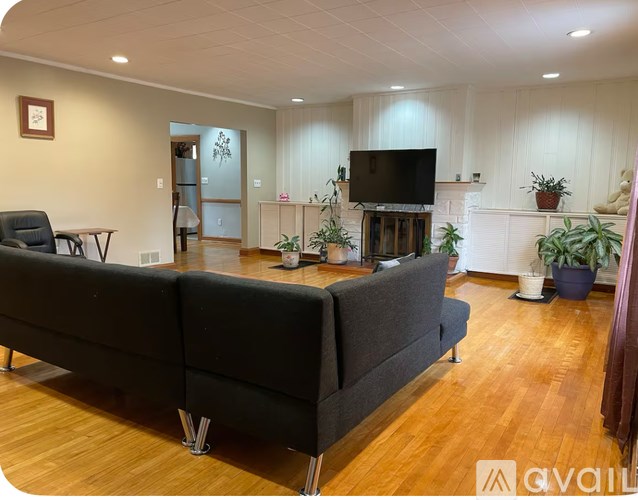 A living room with a black couch and a television on the wall.