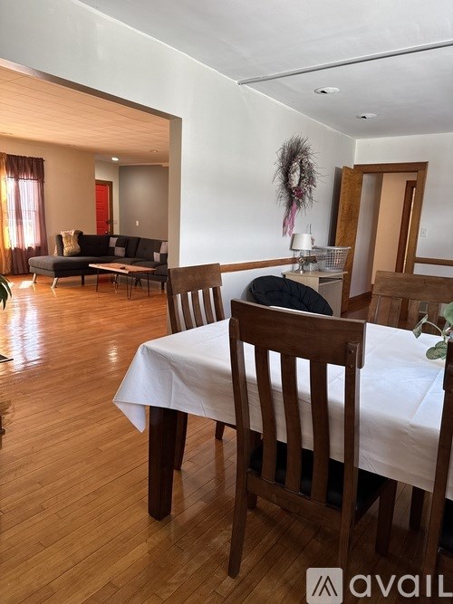 A dining room with a table set for two and a couch in the background.