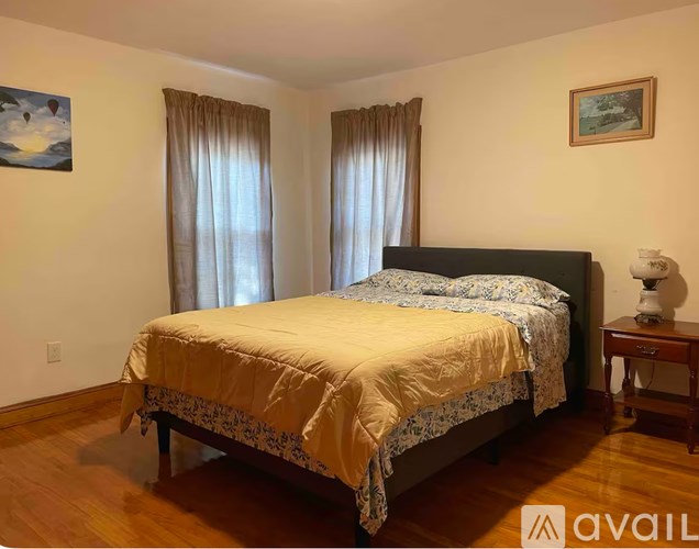 A bedroom with a bed, nightstand, and two pictures on the wall.