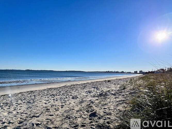 A beach with a clear blue sky and the sun shining brightly.