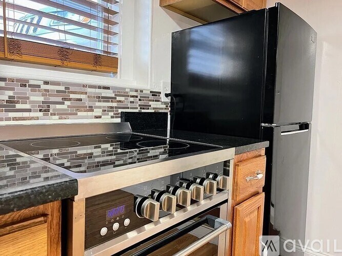 A black refrigerator sits next to a stove in a kitchen.