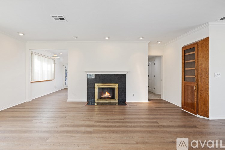 A spacious living room with a fireplace and wooden floors.