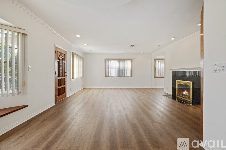 A spacious living room with a fireplace and wooden floors.