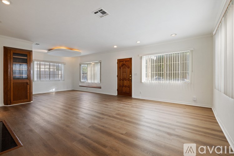 A spacious room with wooden floors and white walls.