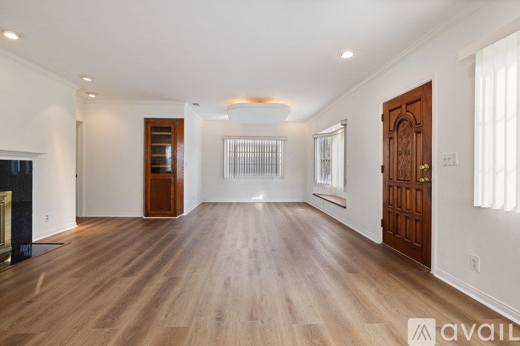 A spacious living room with wooden floors and white walls.