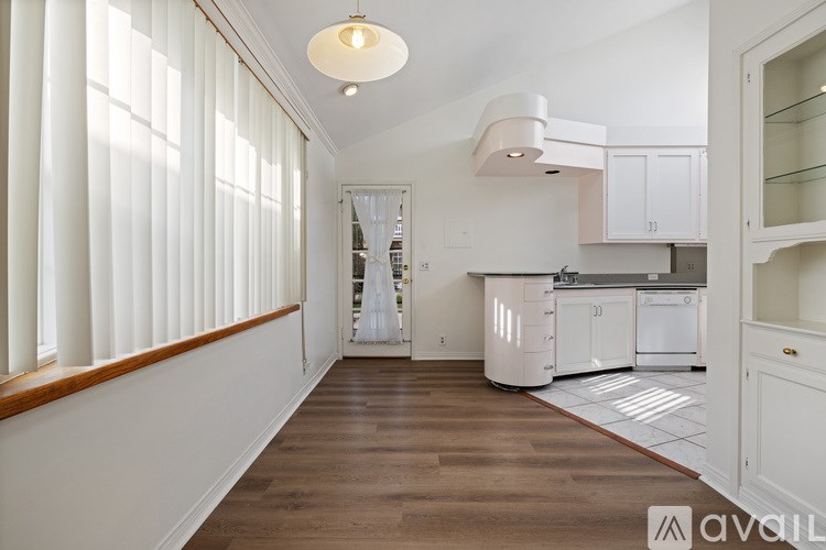 A kitchen with white cabinets and a wooden floor.